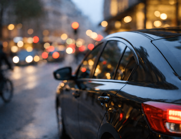Voiture de transport avec chauffeur circulant dans une rue parisienne en fin de journée.