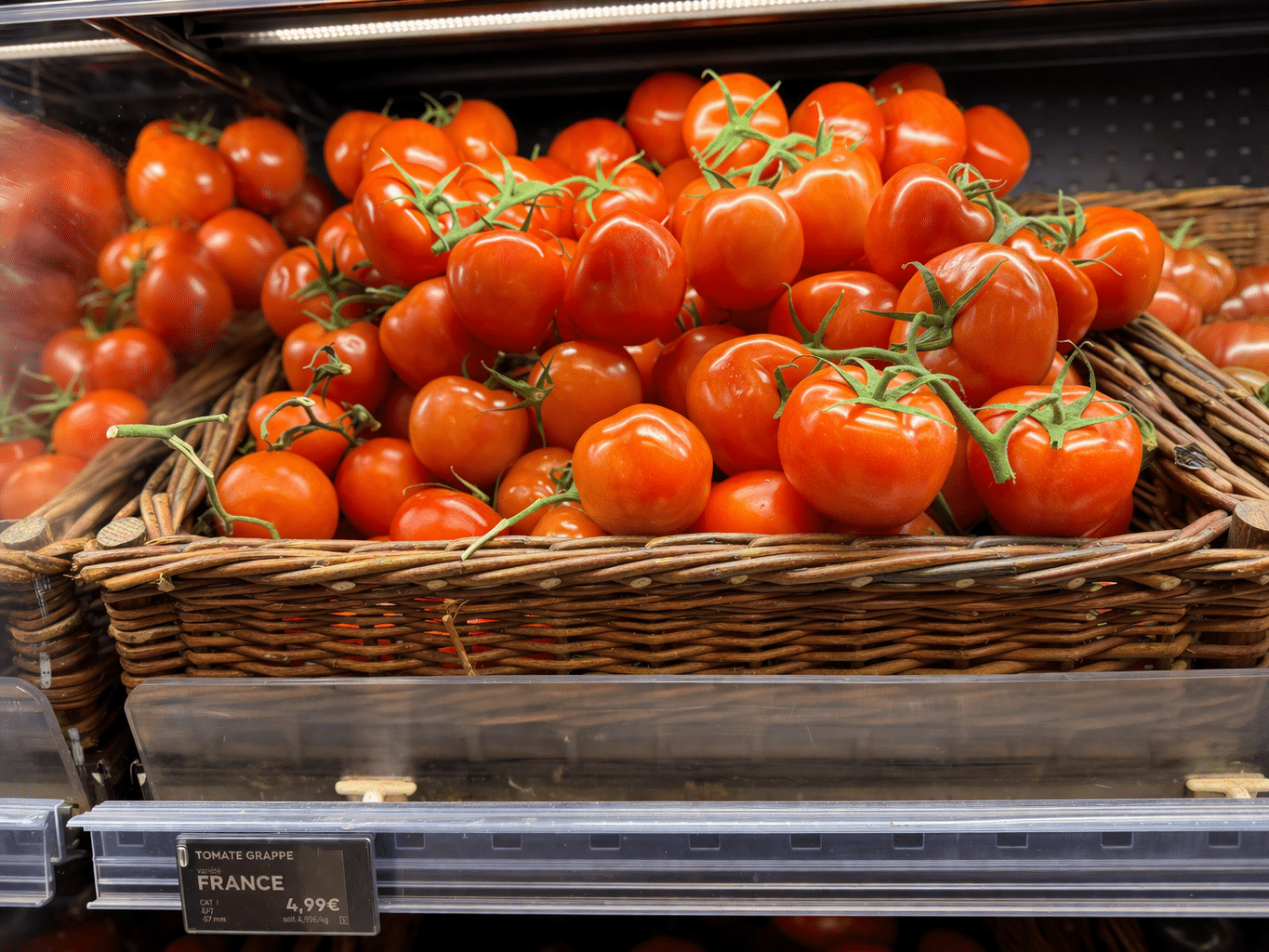 Panier de tomates grappes rouges fraîches avec étiquette France dans un rayon de supermarché