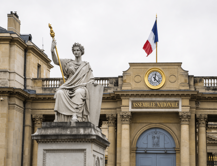 Façade de l’Assemblée nationale à Paris avec statue allégorique et drapeau français