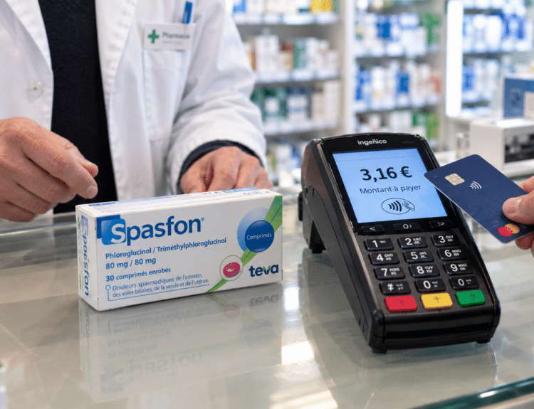 Scène de paiement dans une pharmacie avec une boîte de Spasfon, un terminal bancaire affichant 3,16 € et un patient présentant sa carte.